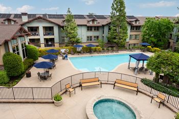 A pool area with a hot tub and loungers.